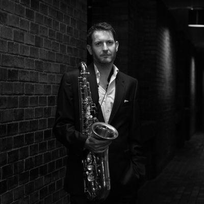 Black and white image of Ollie Weston holding a saxophone